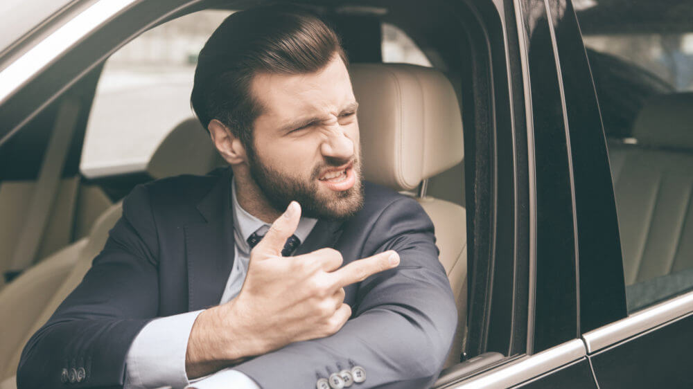 Man giving middle finger in car